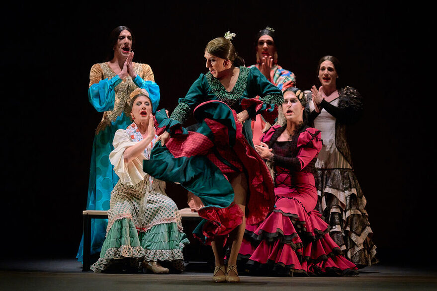 Sechs Flamencotänzer*innen auf der Bühne, eine Person tanzt im Vordergrund der Resr klatscht im Hintergrund.