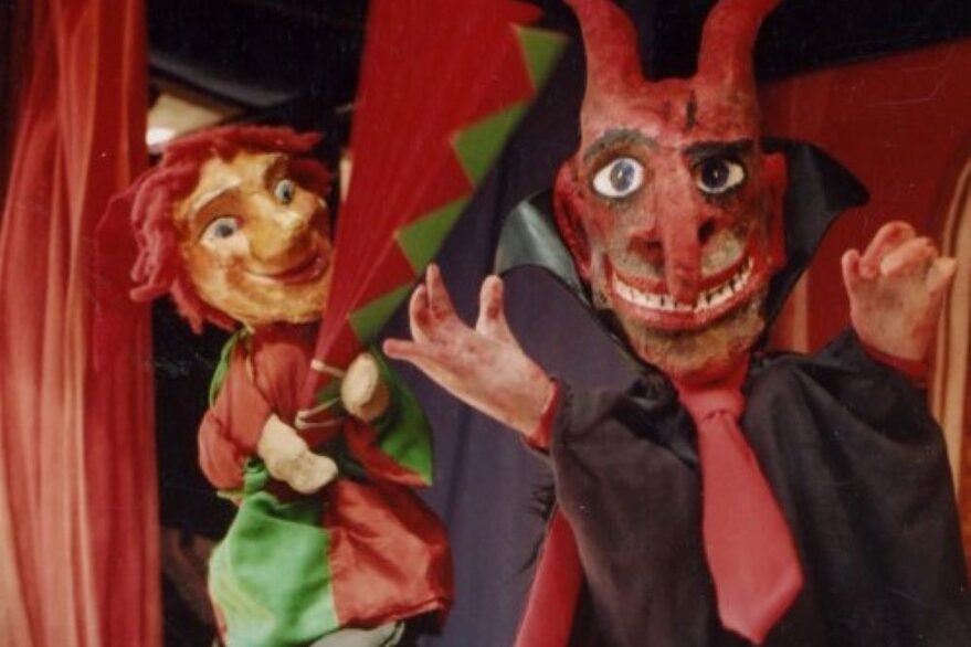 Kasperltheater- zwei Handpuppen vor einem roten Vorhang (links ein Kasperl und rechts ein Teufel).