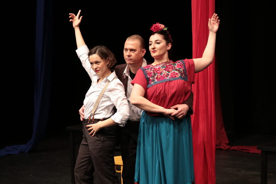 Szenenfoto - dri Personen auf einer Bühne, eine gekleidet wie Frida Kahlo.