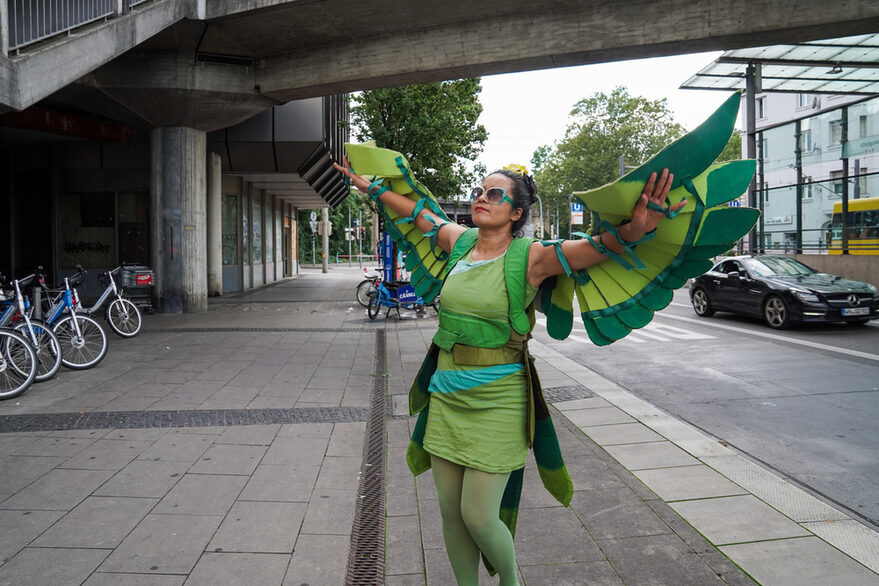 Performerin im Papagei Kostüm am Wilhelmsplatz in Bad Cannstatt