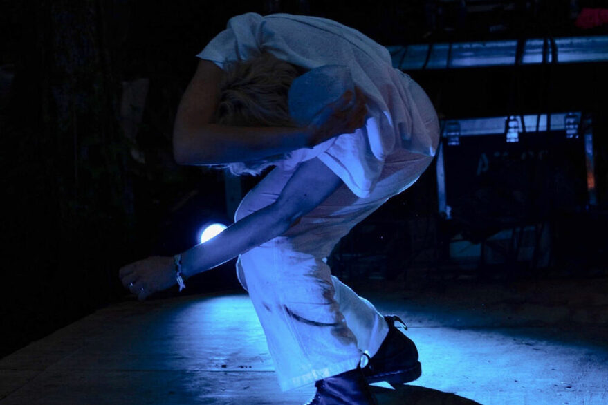 Die Tänzerin Stella Covi tanzt in einem dunklen Raum. SIe ist in blaues Licht getaucht.