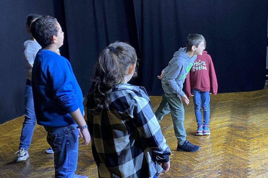 Theaterprobe auf der Bühne: Es sind fünf Kinder zu sehen. Ein Junge verbeugt sich.