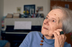 An elderly lady photographed from the side looks up to the left and thinks.