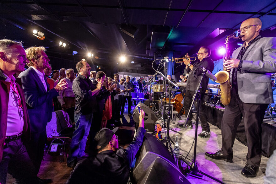 Aufnahme von Jazz-Musizierenden auf einer Bühne und dem Publikum der ersten Reihe auf dem jazzopen Stuttgart