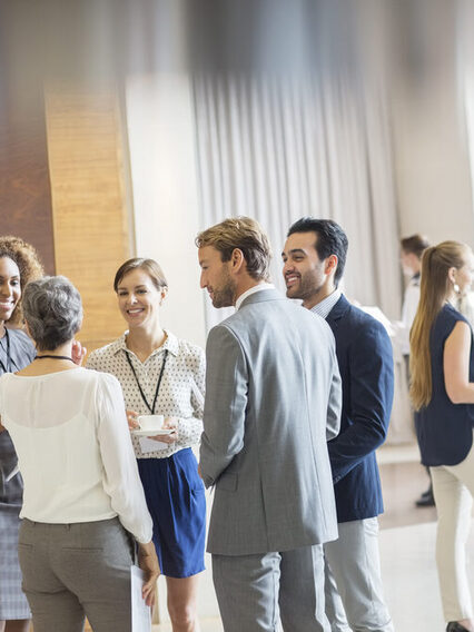Group of business people standing in hall, smiling and talking together