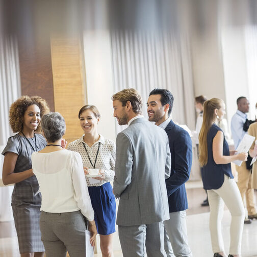 Group of business people standing in hall, smiling and talking together