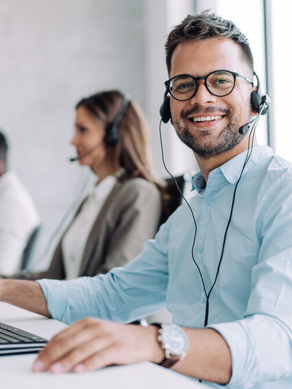 Drei Mitarbeiter sitzen in einem Callcenter.