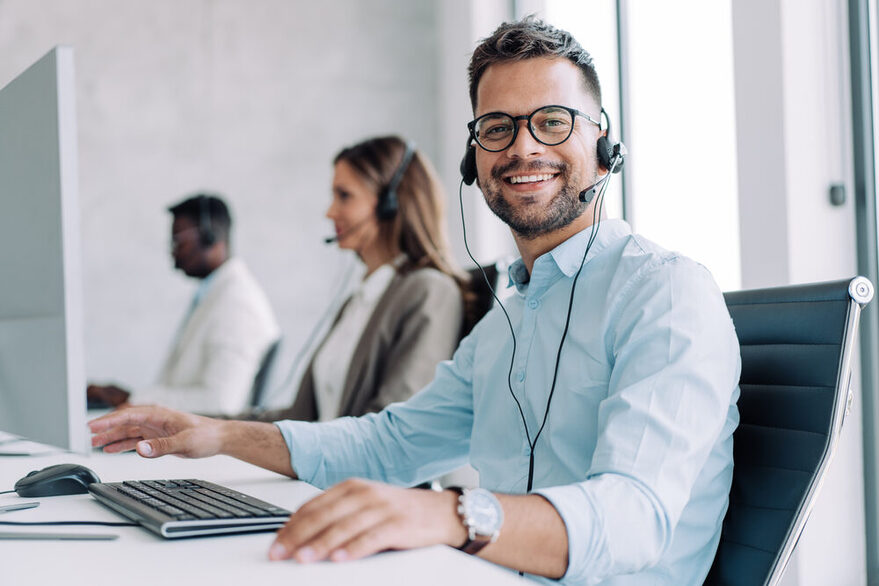 Drei Mitarbeiter sitzen in einem Callcenter.