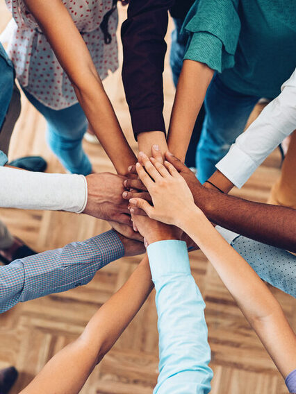 Viele Hände liegen übereinander, die die Einheit und Teamwork zeigen.