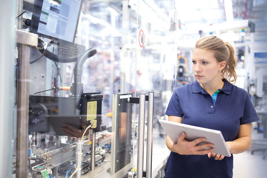 Junge Frau, die in einer modernen Industrieanlage arbeitet.