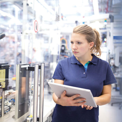 Junge Frau, die in einer modernen Industrieanlage arbeitet.